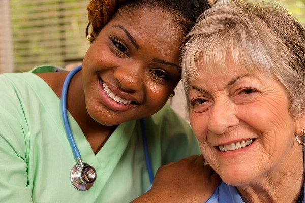 Nurse smiling with an elderly woman during a care visit