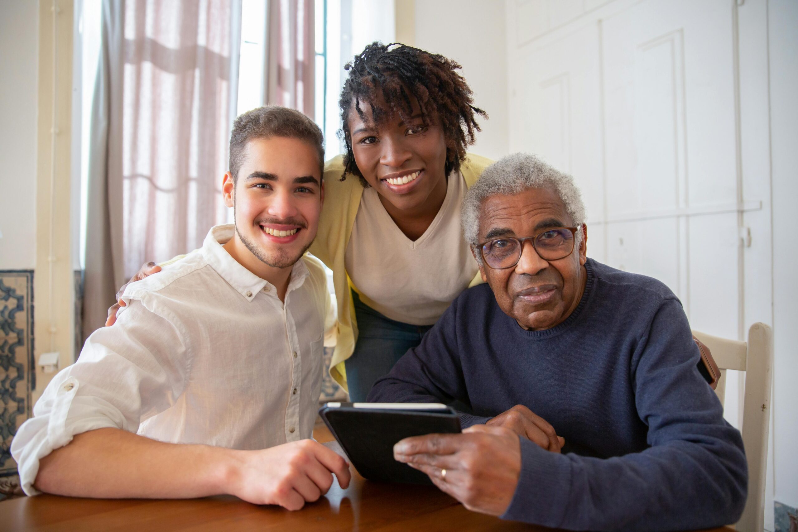 Three people smiling together at a table with a tablet