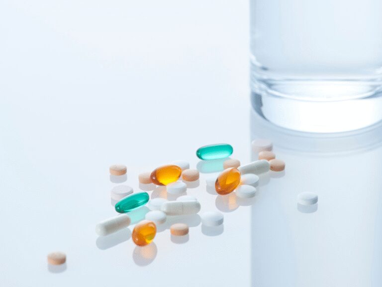 Plain white plastic pill bottle with a screw cap, placed on a neutral beige background.