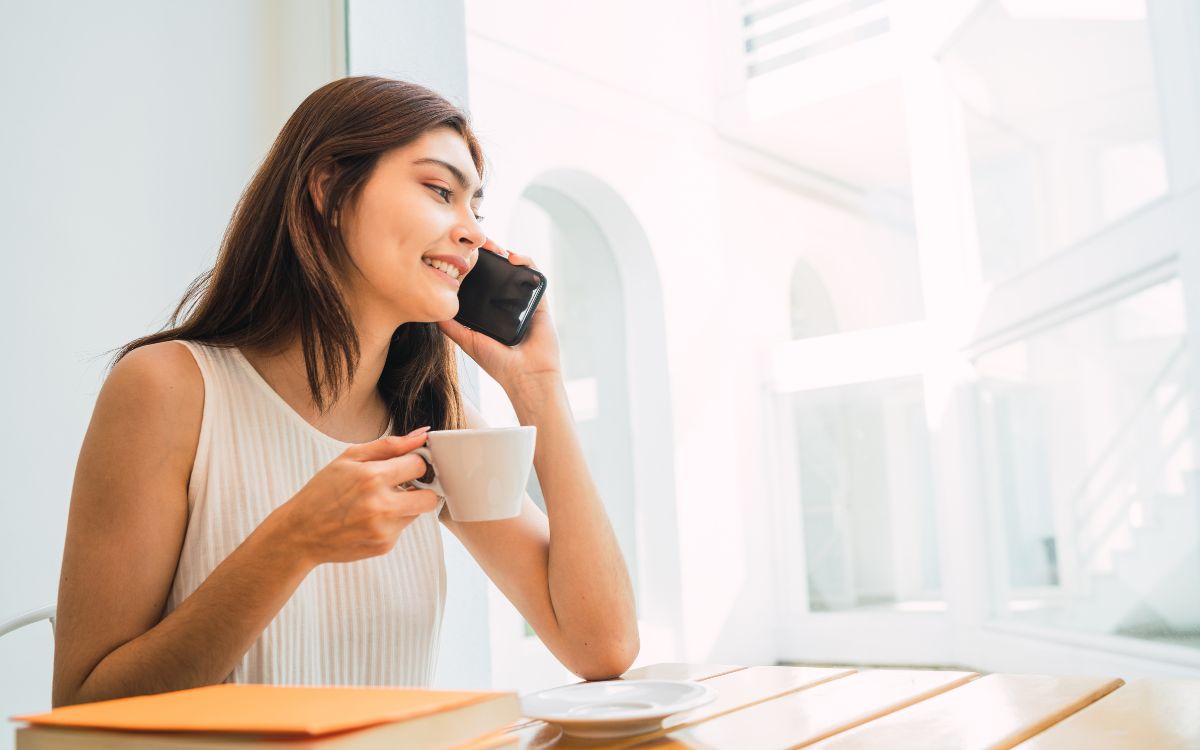 A woman on the phone while holding a cup